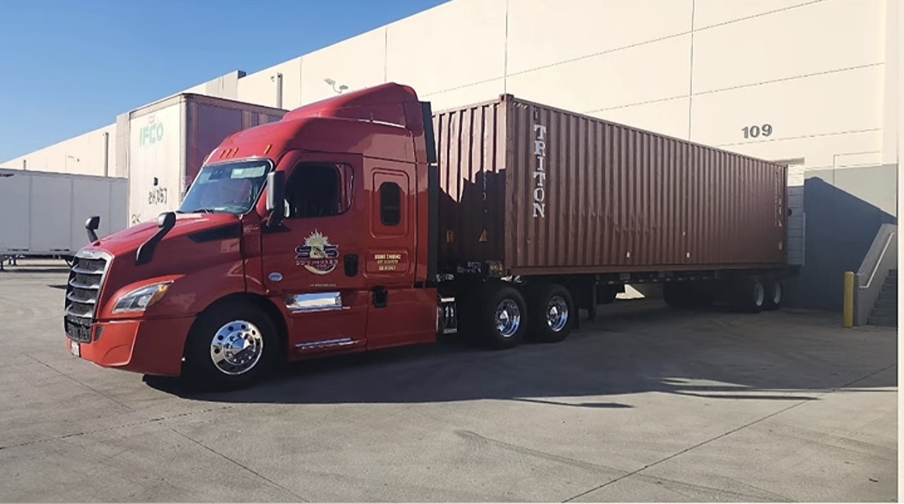 Soltero & Sons red Freightliner with Triton container at warehouse dock